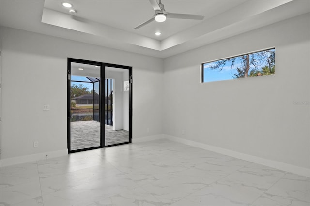 unfurnished room featuring a raised ceiling and ceiling fan