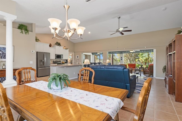 dining room featuring ceiling fan with notable chandelier, decorative columns, vaulted ceiling, and light tile patterned flooring