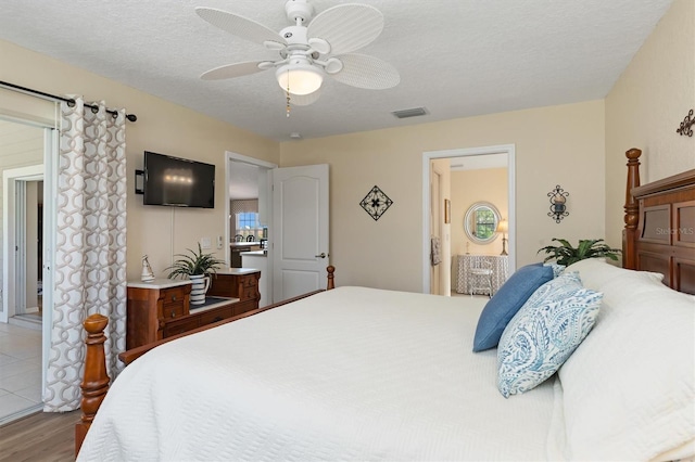 bedroom featuring a textured ceiling, light wood-type flooring, ensuite bathroom, and ceiling fan