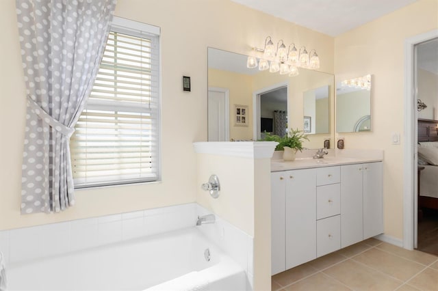 bathroom with tile patterned floors, a wealth of natural light, a bathtub, and vanity