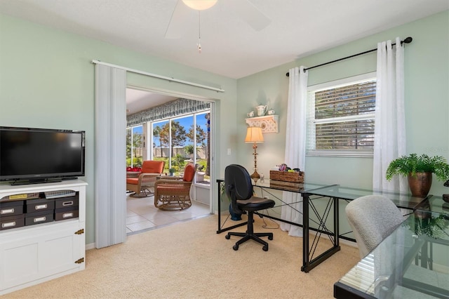 carpeted home office with ceiling fan and a healthy amount of sunlight