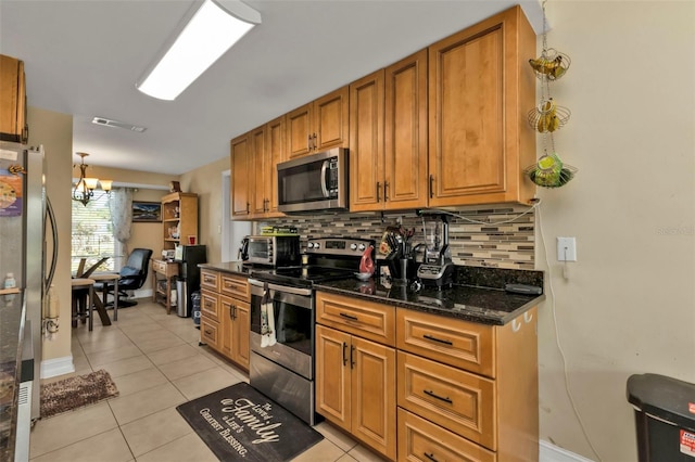 kitchen with appliances with stainless steel finishes, tasteful backsplash, dark stone counters, pendant lighting, and a notable chandelier