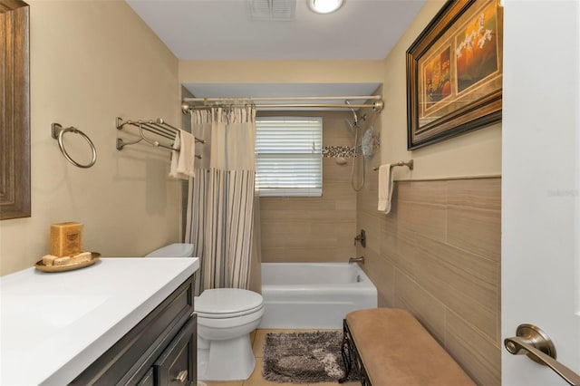 full bathroom with tile patterned flooring, toilet, shower / tub combo with curtain, vanity, and tile walls