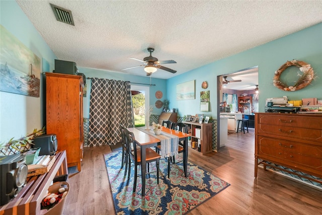 dining space with a textured ceiling and light hardwood / wood-style floors