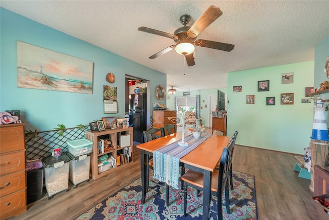 dining area with ceiling fan, dark hardwood / wood-style flooring, and a textured ceiling