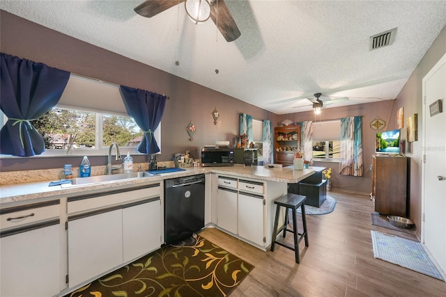 kitchen featuring dishwasher, sink, kitchen peninsula, light hardwood / wood-style floors, and white cabinets