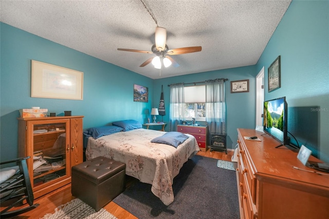 bedroom with hardwood / wood-style floors, a textured ceiling, and ceiling fan