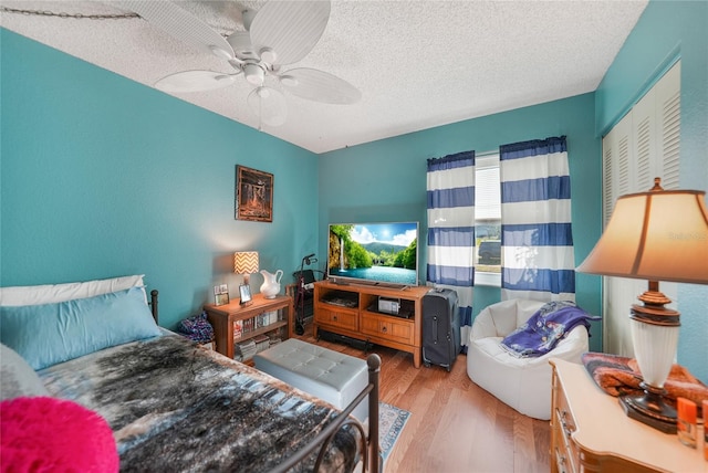 bedroom featuring a closet, a textured ceiling, light hardwood / wood-style floors, and ceiling fan