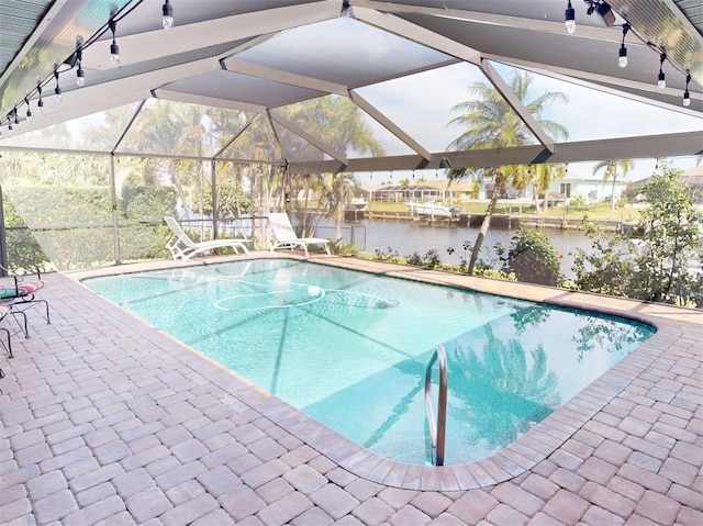 view of pool with glass enclosure, a water view, and a patio