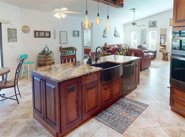 kitchen featuring light stone countertops, sink, stainless steel appliances, vaulted ceiling, and a center island with sink