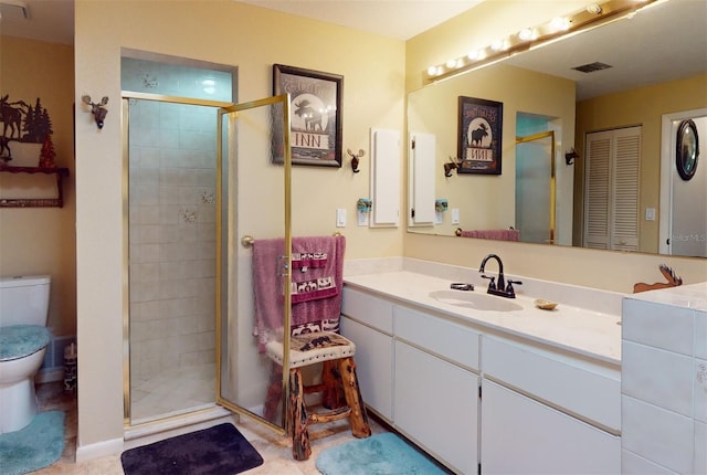 bathroom with tile patterned flooring, vanity, toilet, and a shower with shower door