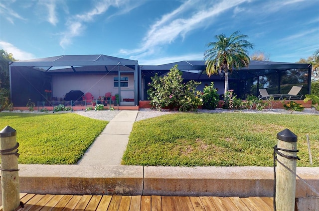 view of front of home featuring glass enclosure and a front lawn