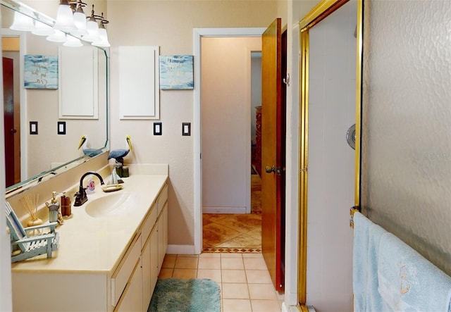 bathroom with a shower with door, vanity, and tile patterned flooring