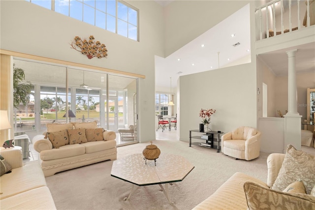 carpeted living room with decorative columns, plenty of natural light, and a towering ceiling