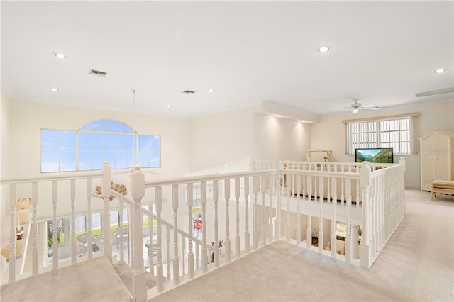 hallway with light colored carpet, crown molding, and a healthy amount of sunlight