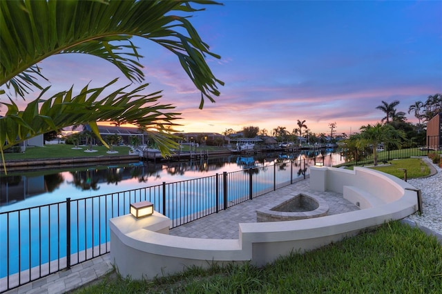 pool at dusk featuring a water view