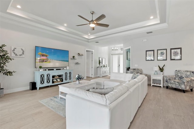 living room with french doors, a raised ceiling, crown molding, ceiling fan, and light hardwood / wood-style floors