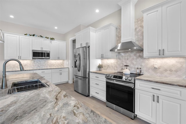 kitchen featuring white cabinetry, sink, stainless steel appliances, and wall chimney range hood