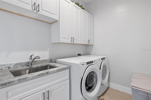 laundry area with washer and clothes dryer, cabinets, light wood-type flooring, and sink