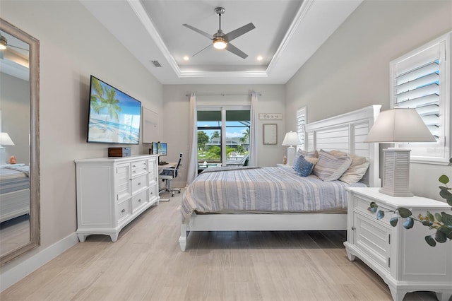 bedroom with light wood-type flooring, a tray ceiling, and ceiling fan