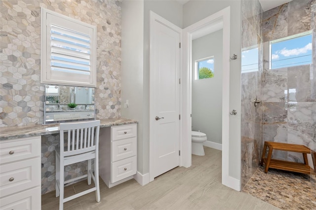 bathroom with tiled shower, wood-type flooring, and toilet