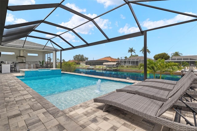 view of pool with an outdoor kitchen, a water view, a patio, and a lanai