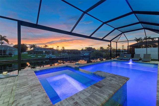 pool at dusk with glass enclosure, a patio area, and an in ground hot tub