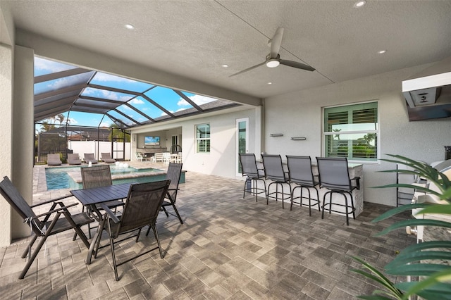 view of patio / terrace with glass enclosure, ceiling fan, and exterior bar