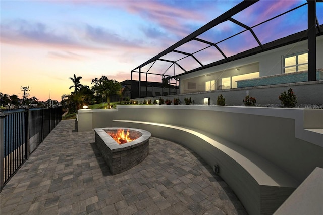 patio terrace at dusk with a fire pit and a lanai