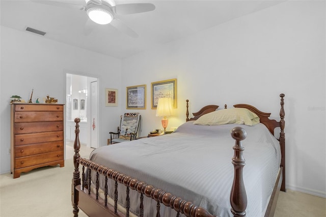 bedroom with ceiling fan, light colored carpet, and connected bathroom