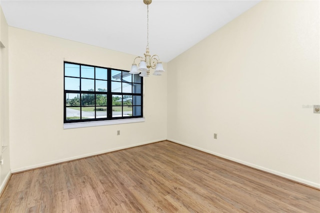 spare room featuring hardwood / wood-style floors and a notable chandelier