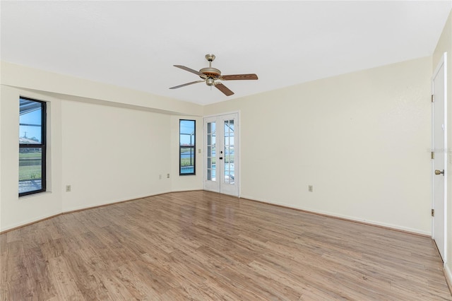 empty room featuring french doors, light wood-type flooring, a wealth of natural light, and ceiling fan