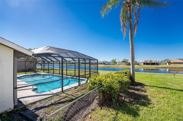 view of swimming pool with glass enclosure, a yard, and a water view