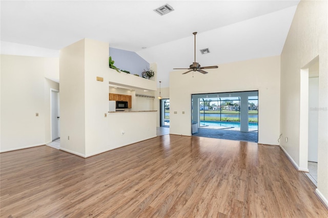 unfurnished living room with ceiling fan, high vaulted ceiling, and wood-type flooring