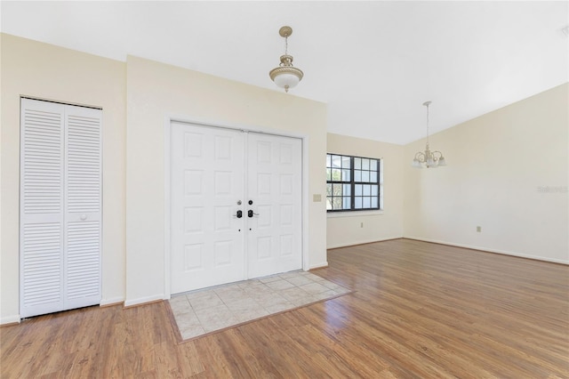 entryway with wood-type flooring and an inviting chandelier