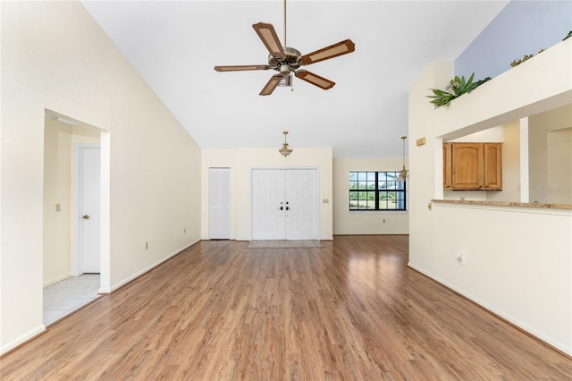 unfurnished living room featuring ceiling fan, light hardwood / wood-style floors, and vaulted ceiling