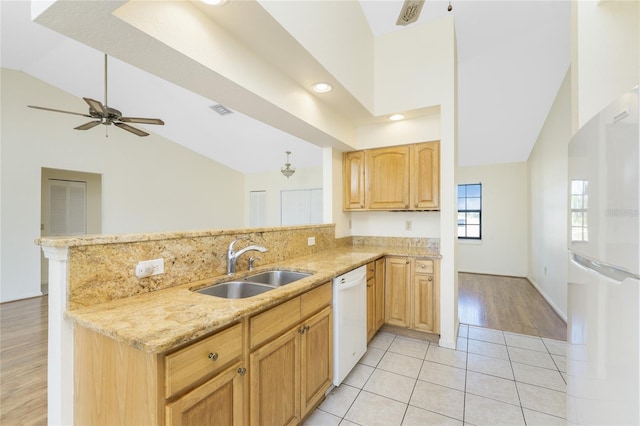 kitchen featuring white appliances, sink, vaulted ceiling, light tile patterned floors, and kitchen peninsula