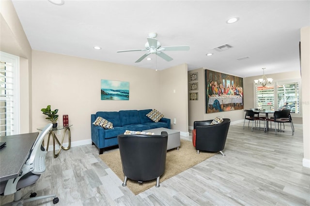 living room featuring light hardwood / wood-style flooring and ceiling fan with notable chandelier