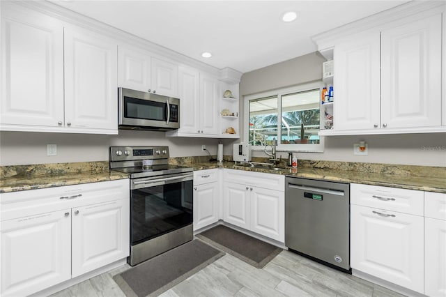 kitchen featuring stainless steel appliances, white cabinetry, dark stone countertops, and sink