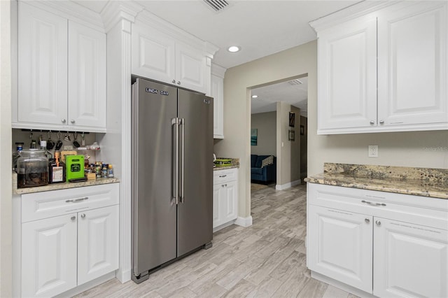 kitchen featuring light hardwood / wood-style floors, light stone counters, white cabinetry, and high quality fridge