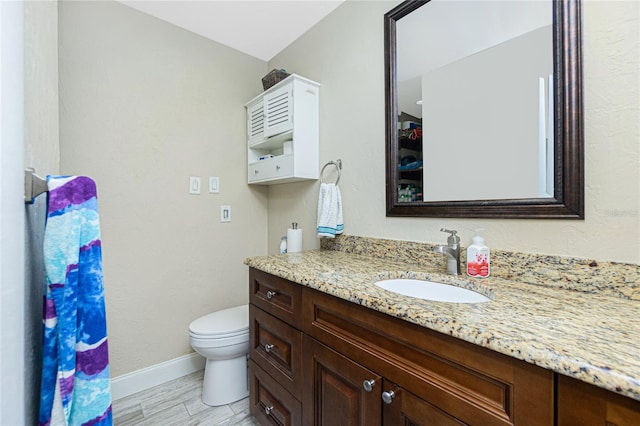 bathroom with wood-type flooring, vanity, and toilet