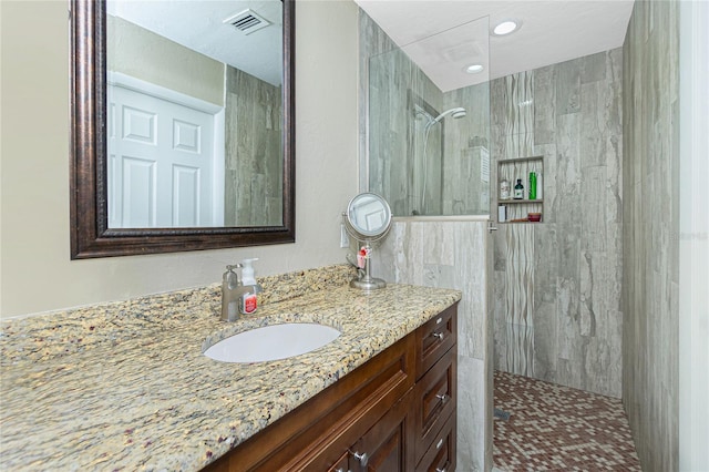 bathroom featuring a tile shower and vanity