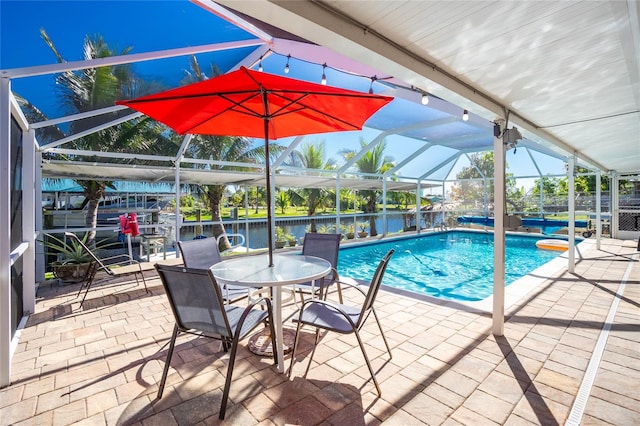 view of pool featuring glass enclosure, a patio area, and a water view