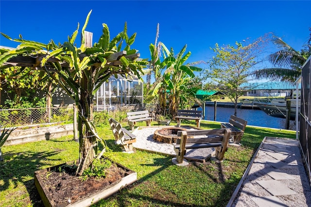 view of yard featuring glass enclosure, a water view, and an outdoor fire pit