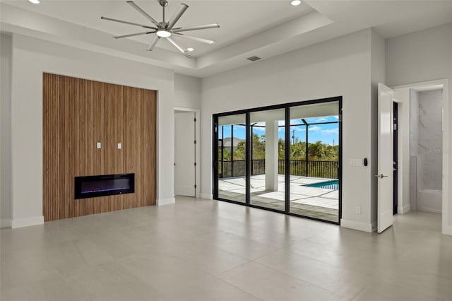 unfurnished living room featuring ceiling fan, a large fireplace, a raised ceiling, a towering ceiling, and light tile patterned flooring