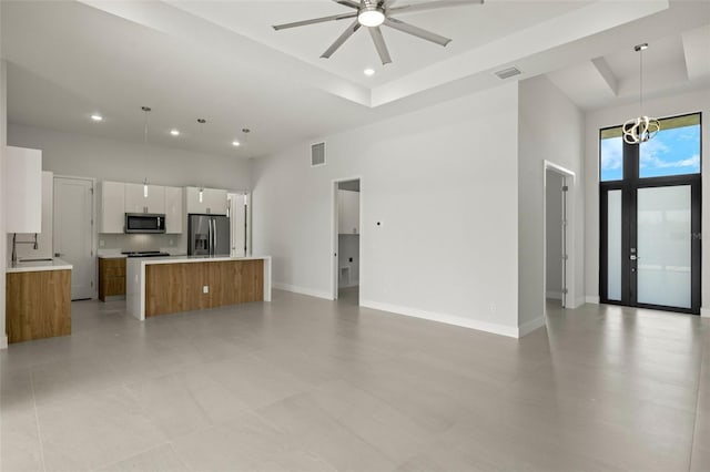 kitchen featuring white cabinetry, stainless steel appliances, decorative light fixtures, a kitchen island, and ceiling fan with notable chandelier