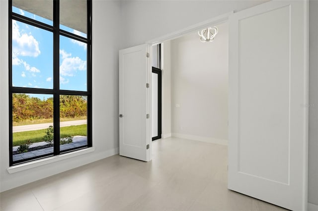 unfurnished room featuring plenty of natural light and an inviting chandelier