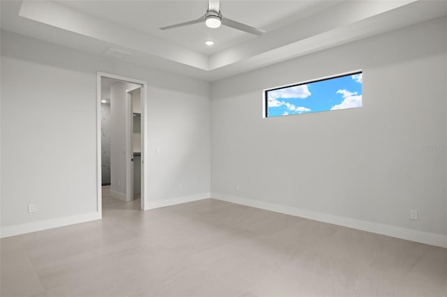 empty room featuring a raised ceiling and ceiling fan