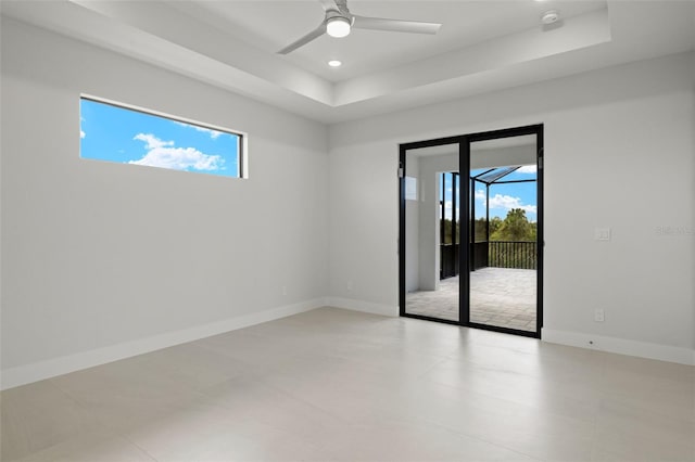 spare room featuring a tray ceiling, plenty of natural light, and ceiling fan