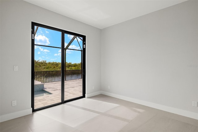 unfurnished room featuring light tile patterned floors and a water view